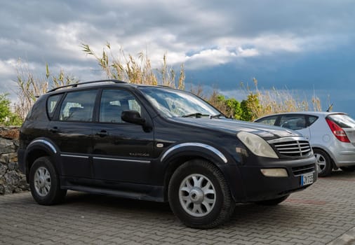 Gaziveren Cyprus -28.02.2025 A sleek black SUV stands parked beside a silver compact car against a backdrop of moody, overcast skies.