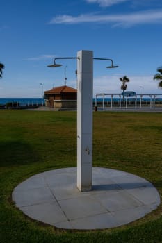 Cool waters flow from an outdoor shower, inviting beachgoers to refresh against a scenic ocean backdrop.