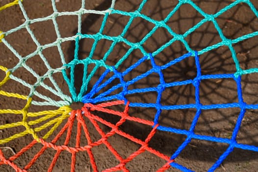 Vibrant threads weave together to create a stunning spiral design, casting vivid shadows on the ground below.