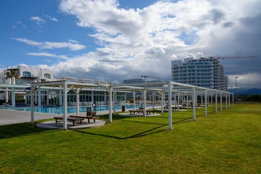 Lush green lawn surrounds a tranquil pool at a contemporary resort, inviting relaxation under a dramatic sky.