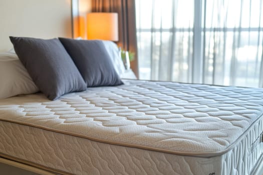 Comfortable mattress and pillows setting on bed with lamp and curtains in bedroom interior design showing hotel room or apartment suite
