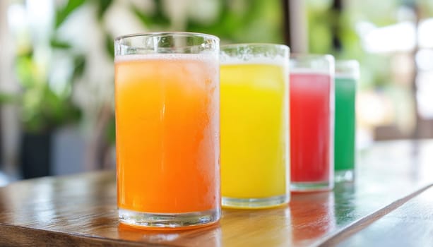 Four colorful refreshing summer drinks with ice are sitting on a wooden table