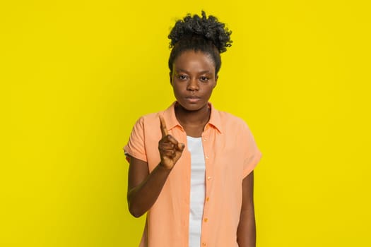 Displeased upset African American woman reacting to unpleasant awful idea, dissatisfied with bad quality, wave hand, shake head No, dismiss idea, don't like proposal. Black girl on yellow background