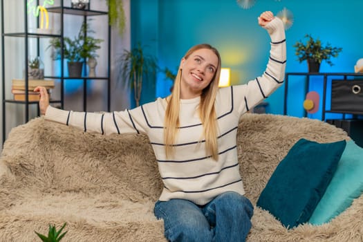 Caucasian woman girl at home sofa stretching body smiling resting after hard stressful workday. Enjoying quiet relaxation comfort gentle relief indoor feeling calm modern lifestyle easy warm cozy mood