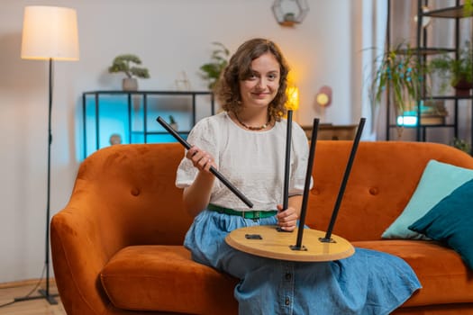 Happy Caucasian woman finishing assembling furniture at home. Successful table desk collect, repair fixing. Young girl after moving into new apartment. Advertisement of a furniture store. Lifestyles.