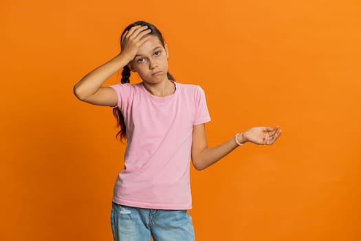 Face palm. Shame on you. Upset sad young preteen child girl kid making face palm gesture, feeling bored, disappointed in result, bad news, disagreement, quarrel. Teenager children on orange background