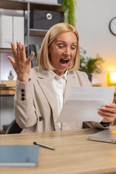 Happy Caucasian mature businesswoman open envelope letter, reading it. Career growth advance promotion, bank loan approval, successful admission to monetary award, long-awaited invitation great news.