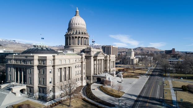 A large building with a dome on top is seen from above. The building is surrounded by a large grassy area and a road. The sky is clear and the sun is shining brightly