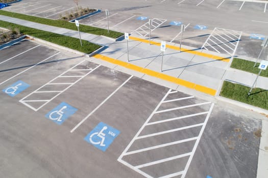 A parking lot with handicap parking spaces and a crosswalk. The parking lot is empty and the handicap parking spaces are marked with blue signs