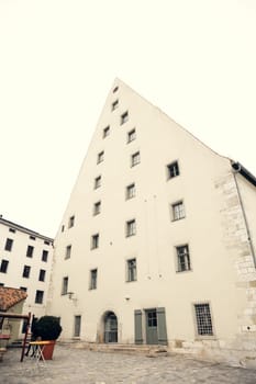 A striking triangular historic building with medieval architecture and multiple windows, located in Regensburg, Germany. Ideal for travel, history, and architectural projects