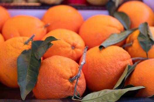 Bright and juicy organic oranges with fresh green leaves in a market setting. Perfect for food photography, organic markets, healthy eating visuals, and citrus-themed designs.