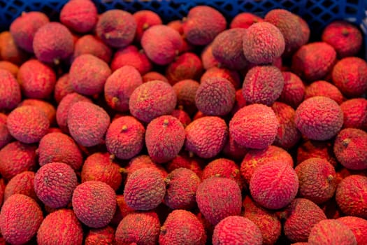 Fresh lychee fruits in a market crate. Exotic tropical fruit with textured skin. Perfect for food photography, tropical fruit visuals, organic produce, and exotic food concepts