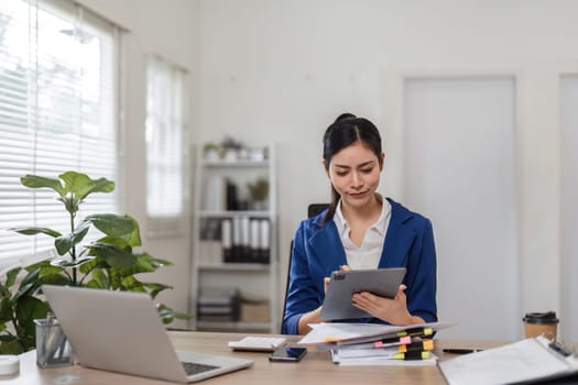 An accountant reviews financial reports on a tablet, showcasing modern technology in her organized workspace.