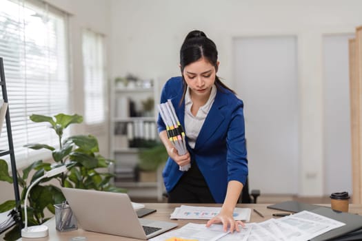 An accountant balances multiple tax files while reviewing financial reports, showcasing her expertise in finance.