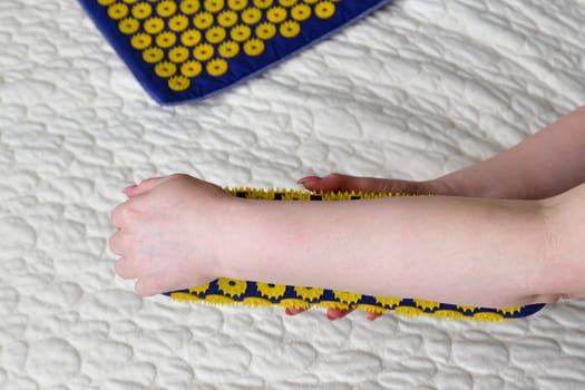 Women's forearm on needle roller - foot massage using an applicator Kuznetsov, Russia