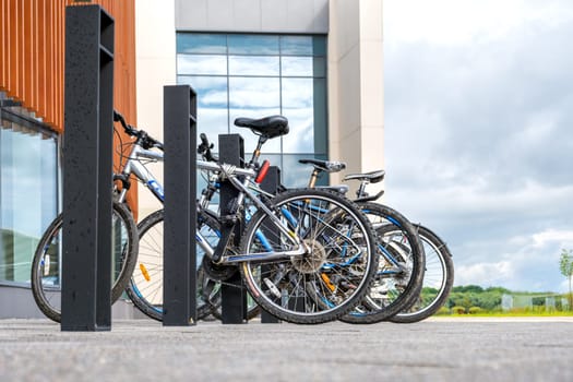 Veliky Novgorod, Russia - 08.01.2024. Bike parking near a modern building in cloudy weather against a backdrop of glass windows and nature.