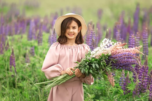 Smiling caucasian young girl in purple flower field holding bouquets.