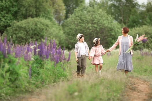 Caucasian family stroll: mother with son and daughter in nature holding flowers.
