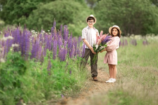 Young caucasian children enjoying nature with wildflower bouquet in summer meadow.