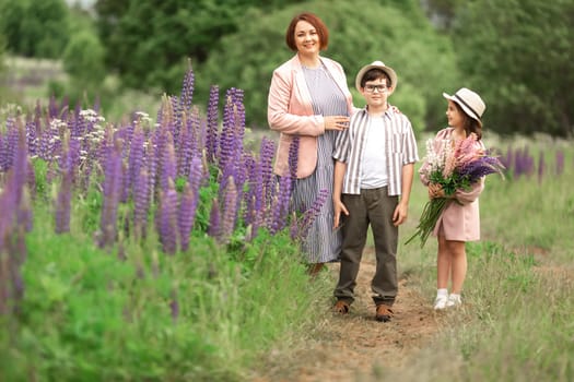 Caucasian mother adult with children in hat and dress walking on nature trail with purple flowers.