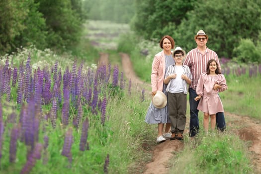 Family of four enjoying nature on a path amid purple flowers in a green forest.