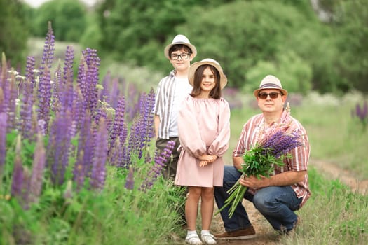 Caucasian family outdoors with adult male and children in flowers field.