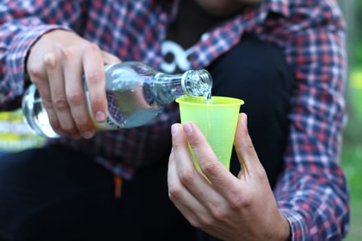 guy pouring alcohol into a plastic cup , sport