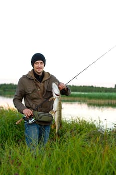 fisherman with spinning rod holds trophy, caught pike , sport