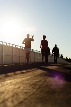 people jogging on a bridge at sunset , sport