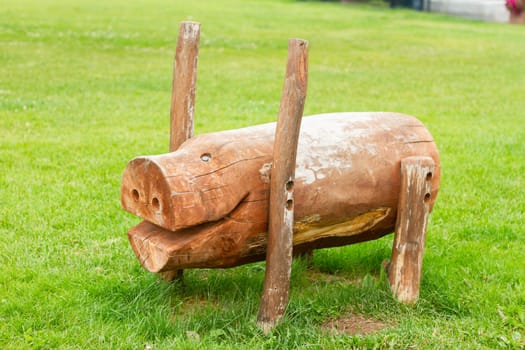 wooden bench in the shape of a pig stands on a green lawn, food
