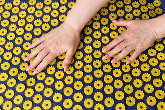 Women's arm on needle mat - massage using an applicator Kuznetsov, Russia