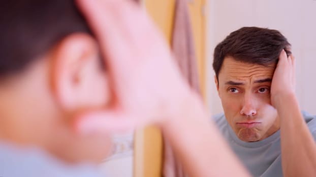 Narcissistic man making faces and admiring himself in the bathroom mirror