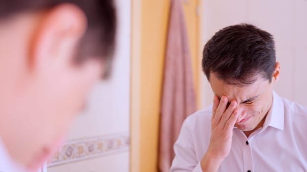 Office worker covering his face with his hand while regretting a mistake in the bathroom