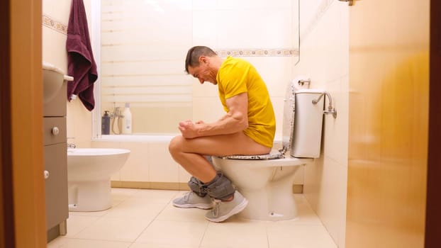 Man experiencing difficulty defecating, straining on the toilet in discomfort