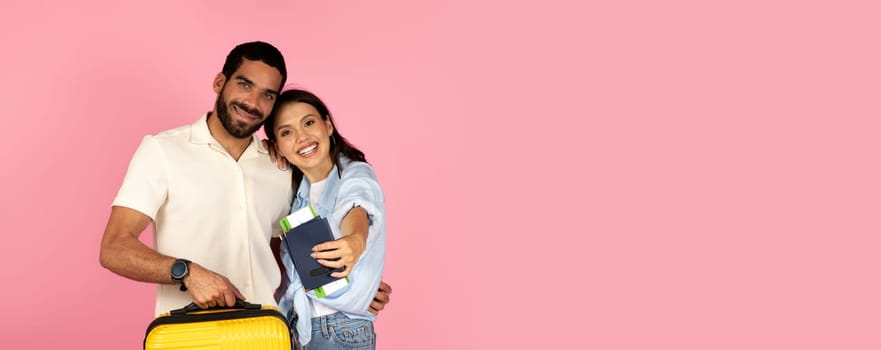 Cute cheerful young hispanic couple travellers going vacation together, carrying luggage, happy man and woman carrying plane tickets and passports, pink background. Summer vacation, trip