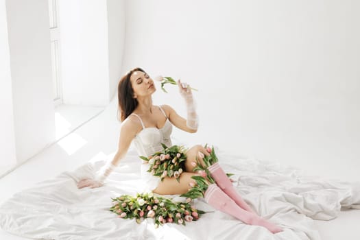 Elegant woman in white lingerie lying on bed with tulips, enjoying flowers in soft natural light, romantic and feminine aesthetic