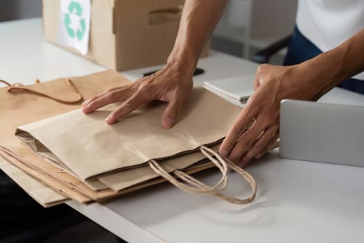 An individual carefully organizes paper bags, demonstrating commitment to recycling and sustainability in their workspace.