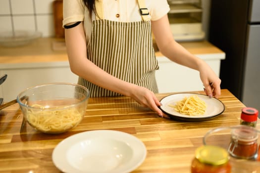 Cropped shot of woman preparing delicious homemade spaghetti in the kitchen.