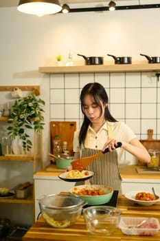 Asian woman stirring rich tomato based sauce on the stove while getting ready to serve freshly prepared pasta dish.