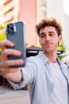 young man taking a selfie with cell phone, he is happy and enjoying the moment, concept of technology of communication and urban lifestyle
