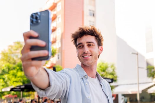 smiling young man taking a selfie with cell phone, he is happy and enjoying the moment, concept of technology of communication and urban lifestyle