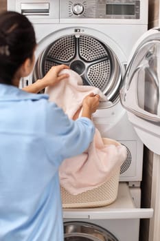 housewife put laundry in automatic washing machine with open door