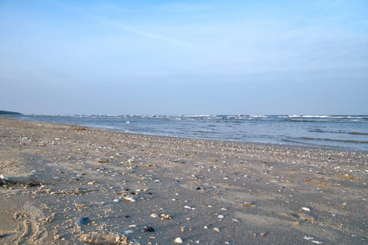 View over the beach on the island of Usedom with lots of shells. Light waves on the Baltic Sea. Landscape shot of the coast