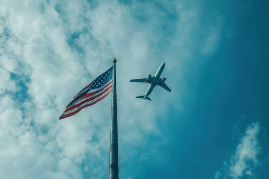 US flag on a pole with a passenger plane flying high in the sky in the background