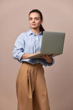 Caucasian pretty freelancer business woman in blue shirt using laptop for work, e-learning, e-banking or online shopping on beige background