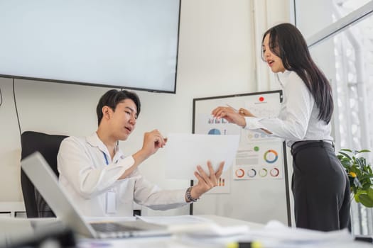 A professional reviews financial documents while discussing tax strategies with a colleague in a bright office space.