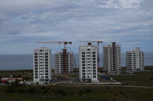 New residential towers rise against a dramatic sky, showcasing progress near the ocean's edge in a coastal community.
