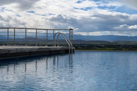 Calm waters reflect the beauty of distant mountains while gentle clouds drift above, creating a tranquil escape.