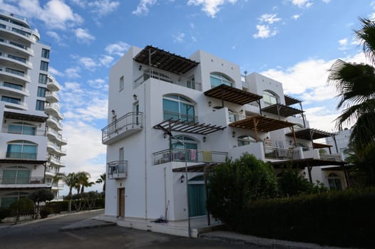 Contemporary buildings stand against a stunning sky, surrounded by lush greenery and a relaxed coastal atmosphere.