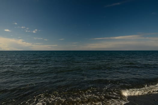 Waves gently lap the shore as twilight casts a warm glow over the tranquil ocean landscape.